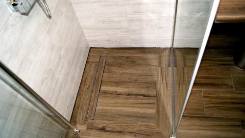 a shower with a glass door and wooden floor at Mini Studio in Augustów