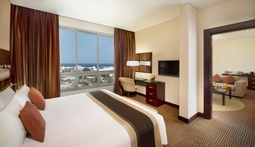 ein Hotelzimmer mit einem Bett und einem großen Fenster in der Unterkunft City Seasons Hotel & Suites Muscat in Muscat