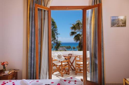 a bedroom with a view of the ocean from a balcony at Dionyssos Rooms Preveli Crete in Preveli