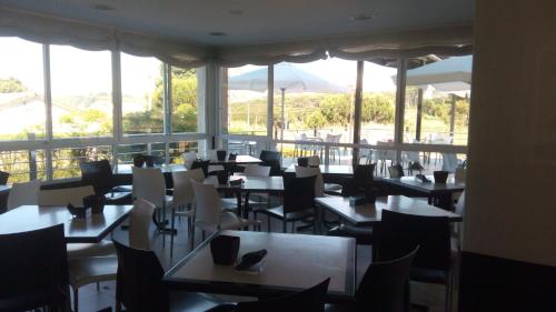 um restaurante com mesas, cadeiras e janelas em Hotel Ronsel em Montalvo