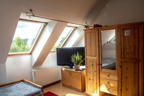 a attic room with a tv and a wooden cabinet at Apasjonata in Świdnica