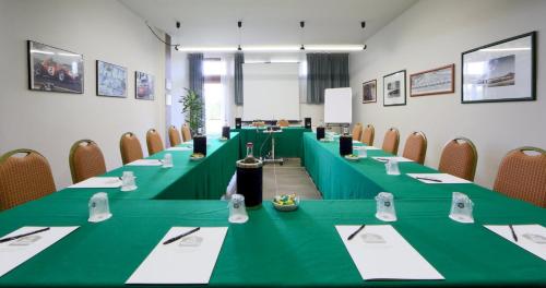 a conference room with long green tables and chairs at Best Western Modena District in Campogalliano