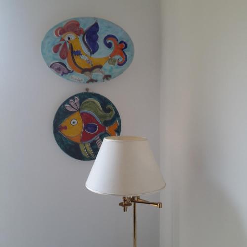 a lamp and plates on a wall with a chicken on it at Elegant and Sea View Excelsior Apartment in Levanto