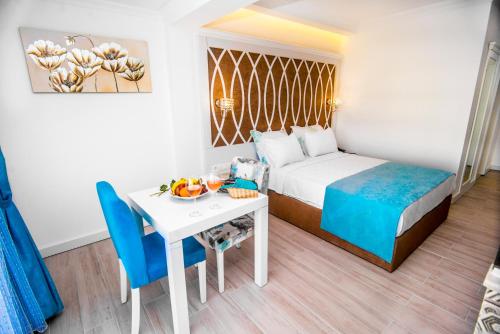 オルデニズにあるOcean Blue High Class Hotel & SPAのベッド、テーブル、椅子が備わるホテルルームです。