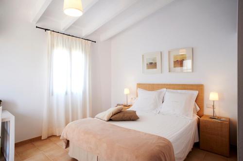 a bedroom with a bed with white sheets and a window at son capellot in Felanitx