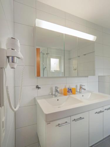 a white bathroom with a sink and a mirror at Apart Holidays - Residenza Flora in Locarno