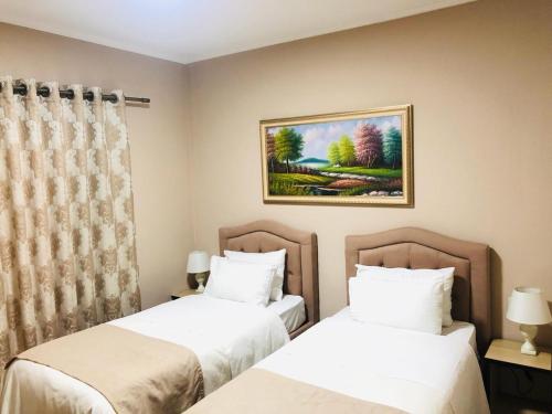Un dormitorio con dos camas y un cuadro en la pared. en Centrum Hotel, en Tirana