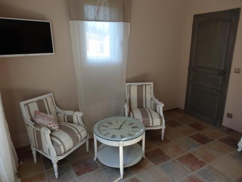 a living room with two chairs and a clock on a table at Mas'Xime in Saint-Rémy-de-Provence