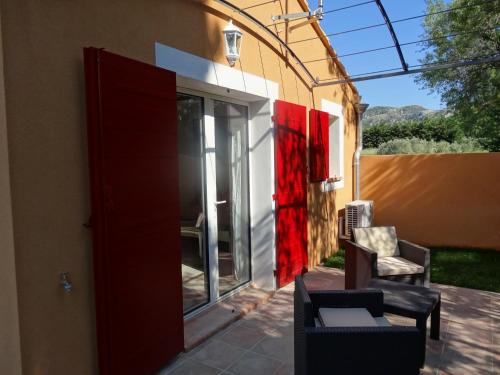 a patio with a red door and two chairs at Mas'Xime in Saint-Rémy-de-Provence