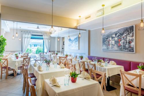 a dining room with white tables and chairs at Hotel Argegno in Argegno