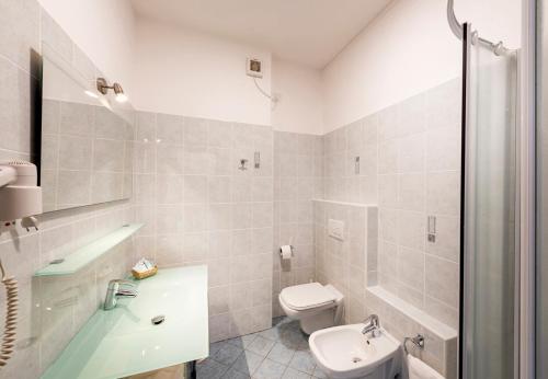 a bathroom with a toilet and a tub and a sink at Hotel Argegno in Argegno