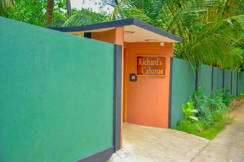 an orange and green building with a sign on it at Richards Cabanas in Tissamaharama
