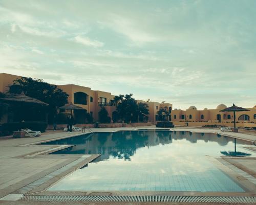 a large swimming pool in a courtyard with buildings at Pool View One bedroom Apt - B103 in Hurghada