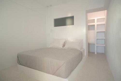 een witte slaapkamer met een bed en een televisie bij Meltemi Seaside in Kampos Paros