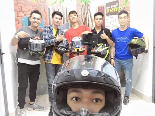 a group of men standing around a boy in a motorcycle helmet at Peaceful House Hostel in Dong Hoi