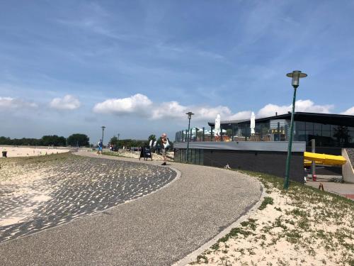 a person walking a dog on a sidewalk next to a beach at Marina Strand Appartement Lemmer in Lemmer