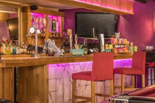 a bar with two red chairs and a tv at The Saracens Head THE CONKERA in Chapel Saint Leonards