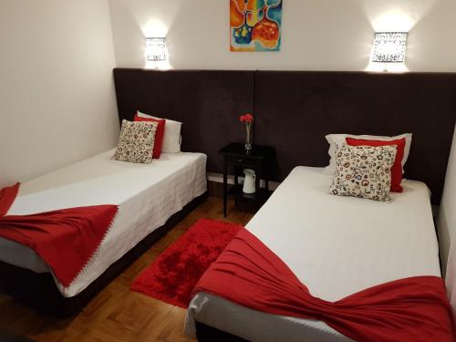 een kamer met 2 bedden met rode en witte kussens bij Alojamento Ar e Sol in Guimarães