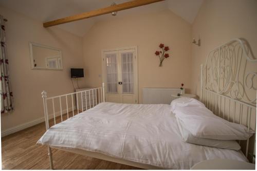 a bedroom with a white bed with a wooden floor at Saracens Head Old Function Room in Chapel Saint Leonards