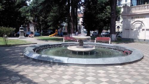 a fountain in the middle of a park with two benches at Apartament in the centre batumi in Batumi