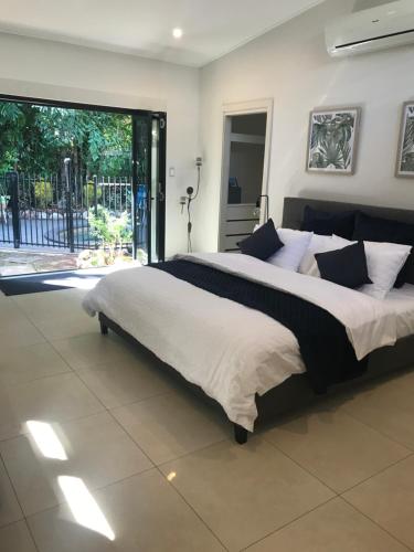a large bed in a bedroom with a large window at The Tropical Sanctuary in Darwin