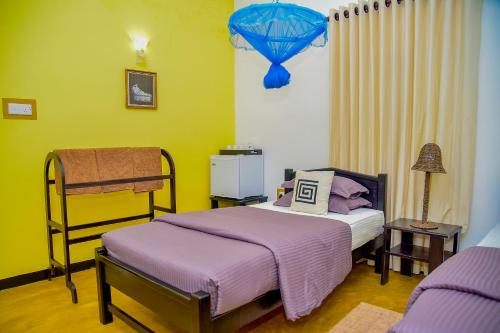 a bedroom with a bed with purple sheets and a lamp at Richards Cabanas in Tissamaharama