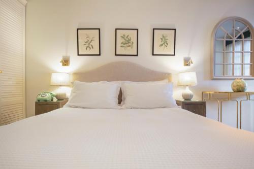 a bedroom with a large white bed with two lamps at Despotiko Hotel in Mýkonos City