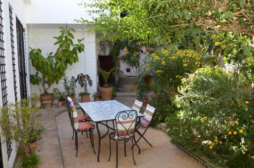 a table and chairs in a garden with plants at RIAD OASIS D'ASILAH in Asilah