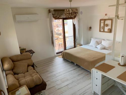 a bedroom with a bed and a couch at Vapori Otel in Bozcaada