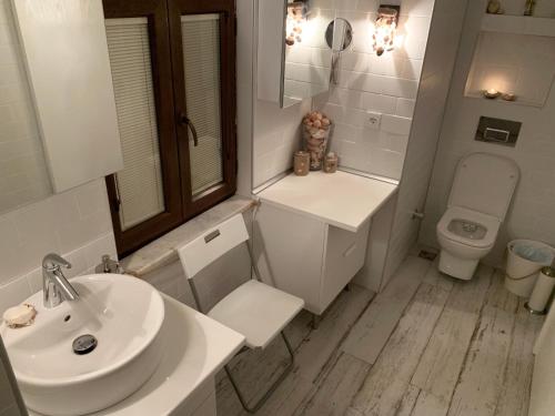a white bathroom with a sink and a toilet at Vapori Otel in Bozcaada