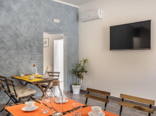 a dining room with a table and a television on a wall at L'Antico Borgo B&B in Noto