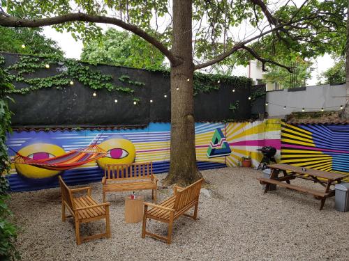 a group of benches and a tree in front of a wall at Popcorn Hostel in Bucharest