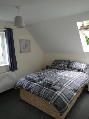 1 dormitorio con 1 cama con manta a cuadros en 2 Wood Yard Cottages, Red Mayes Farm, en Spalding
