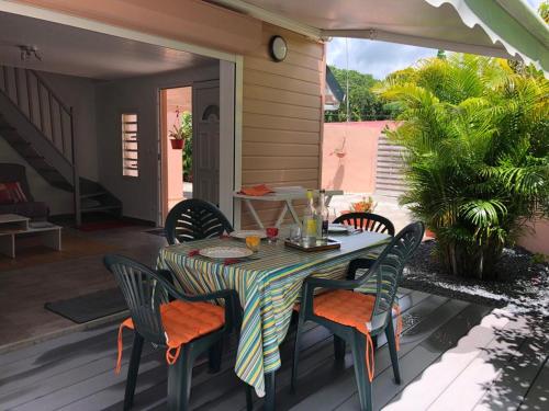 a patio with a table and chairs on a deck at Cap Colibri in Petit-Bourg