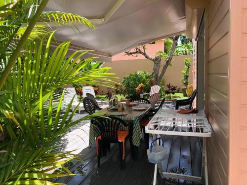 een patio met een tafel, stoelen en planten bij Cap Colibri in Petit-Bourg