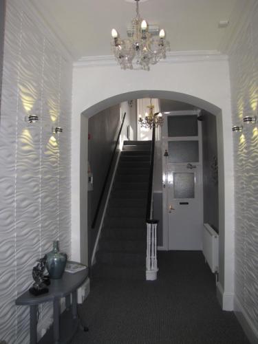 a hallway with a staircase with a chandelier at Ashmira Guest House in Weymouth
