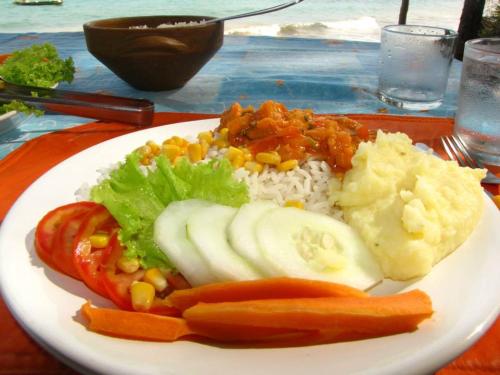 a plate of food with rice and vegetables on a table at Pousada Doze Cabanas in Japaratinga
