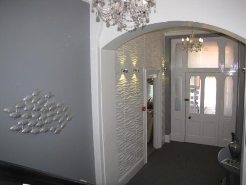 a hallway with a chandelier and a white wall at Ashmira Guest House in Weymouth