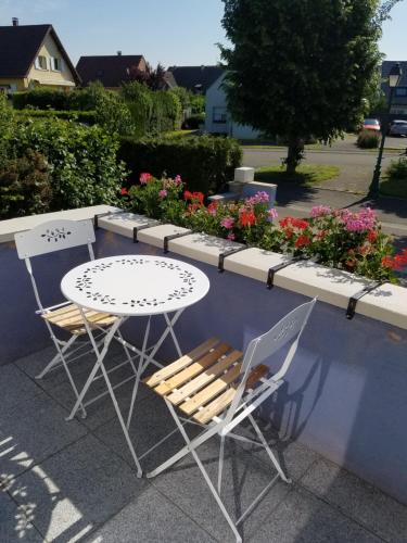 a table and two chairs and a table with flowers at Les mésanges de l'Ill in Andolsheim