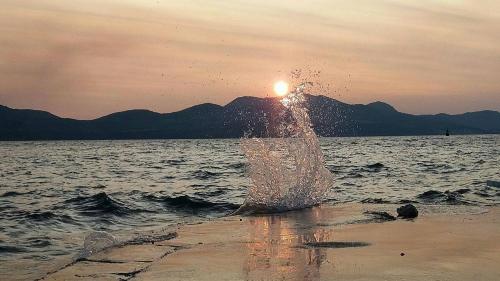 a splash of water on the beach at sunset at Apartmani Urlic in Sreser