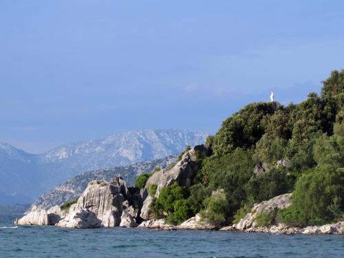 an island in the water with trees and rocks at Apartmani Urlic in Sreser