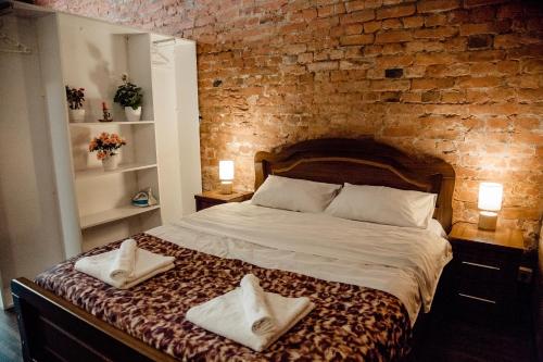 1 dormitorio con pared de ladrillo y 1 cama con 2 toallas en Tbilisi Apartment en Tiflis