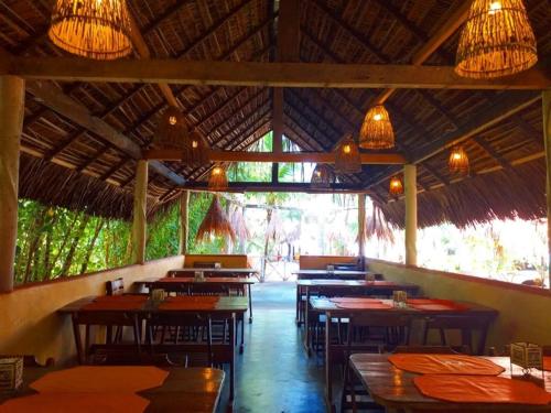 um restaurante com muitas mesas, cadeiras e luzes em Pousada Doze Cabanas em Japaratinga