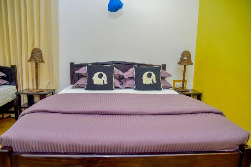a bedroom with a large bed with purple sheets and pillows at Richards Cabanas in Tissamaharama