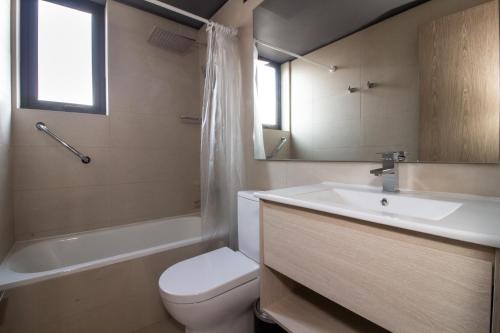 a bathroom with a sink and a toilet and a bath tub at One Nk Apartments in Santiago