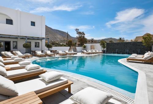 a swimming pool with chaise lounge chairs and a resort at Amara Suites Santorini in Kamari