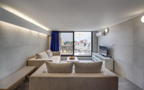 a living room with two couches and a large window at Gevoni Deluxe Suites in Ayia Napa