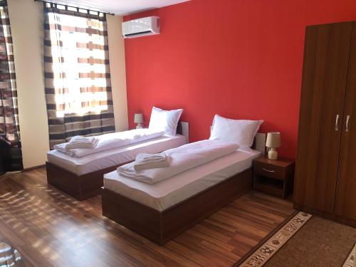 two beds in a room with a red wall at Amigos in Pawlikeni