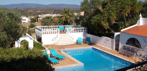 a swimming pool with chairs and a house at Vivenda Balou in Silves