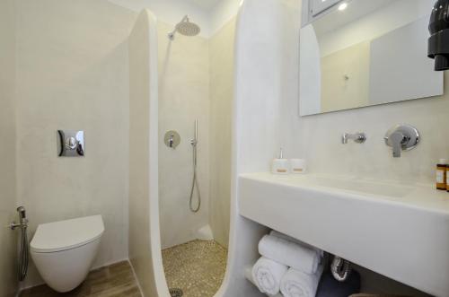 a white bathroom with a toilet and a sink at Prestige on the beach in Naxos Chora